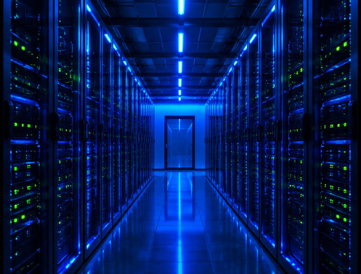 Data center corridor lined with server racks illuminated in blue